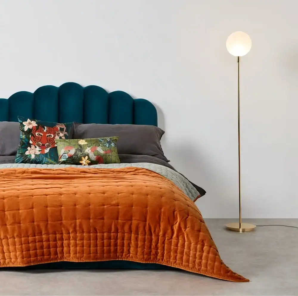 Orange velvet throw on a bed with a navy headboard. Make your bedroom look expensive