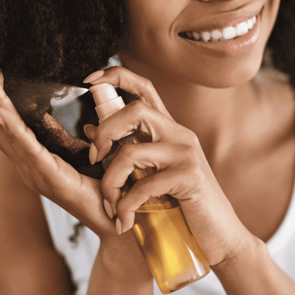 Up close shot of smiling woman spraying hair with oil