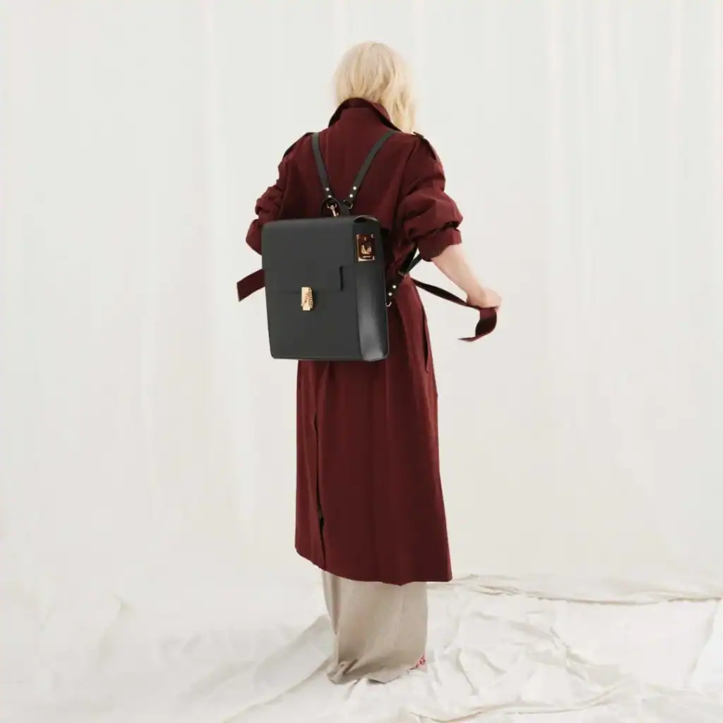 Back view of a blonde wearing a wine red parka coat and a back vegan leather backpack
