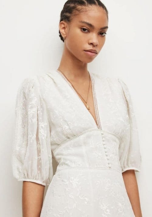 Model wearing a white dress with button front detail