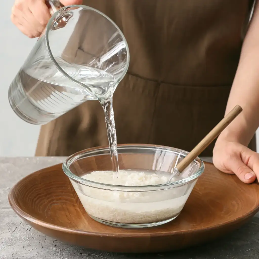 Person Preparing Rice Water on Table