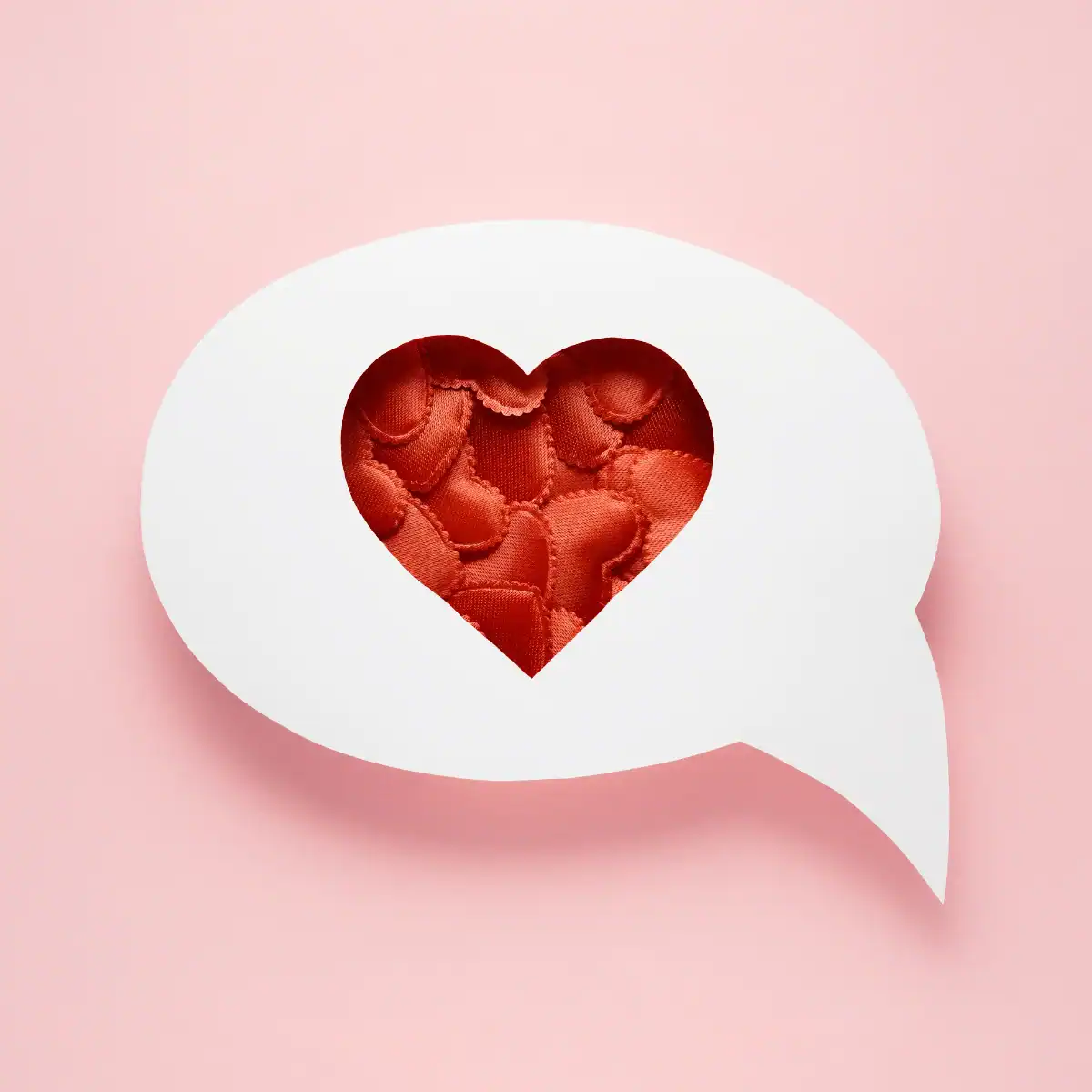 Small-red-cushion-hearts-inside-a-white-speech-bubble.-Background-is-plain-pink
