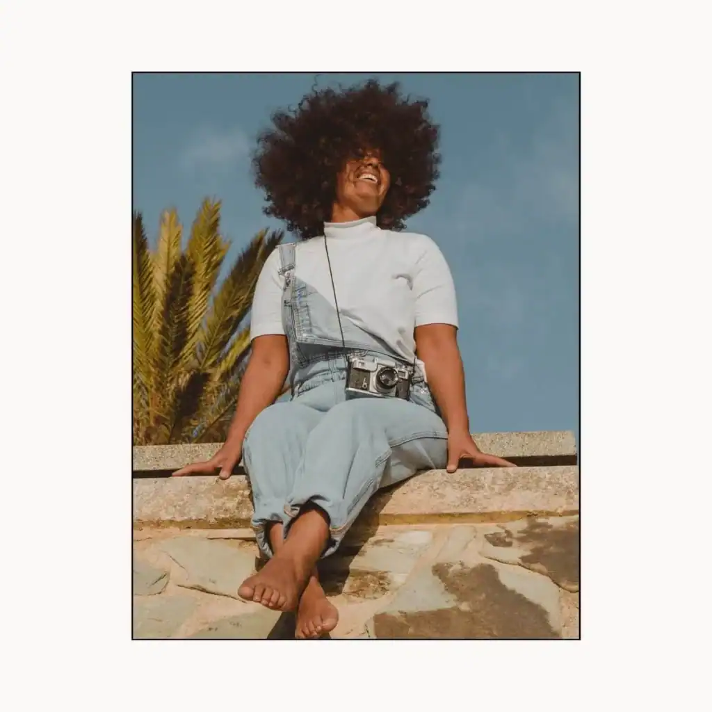 Smiling-woman-with-a-vintage-camera-sitting-on-a-wall.-Positivity-Instagram-captions