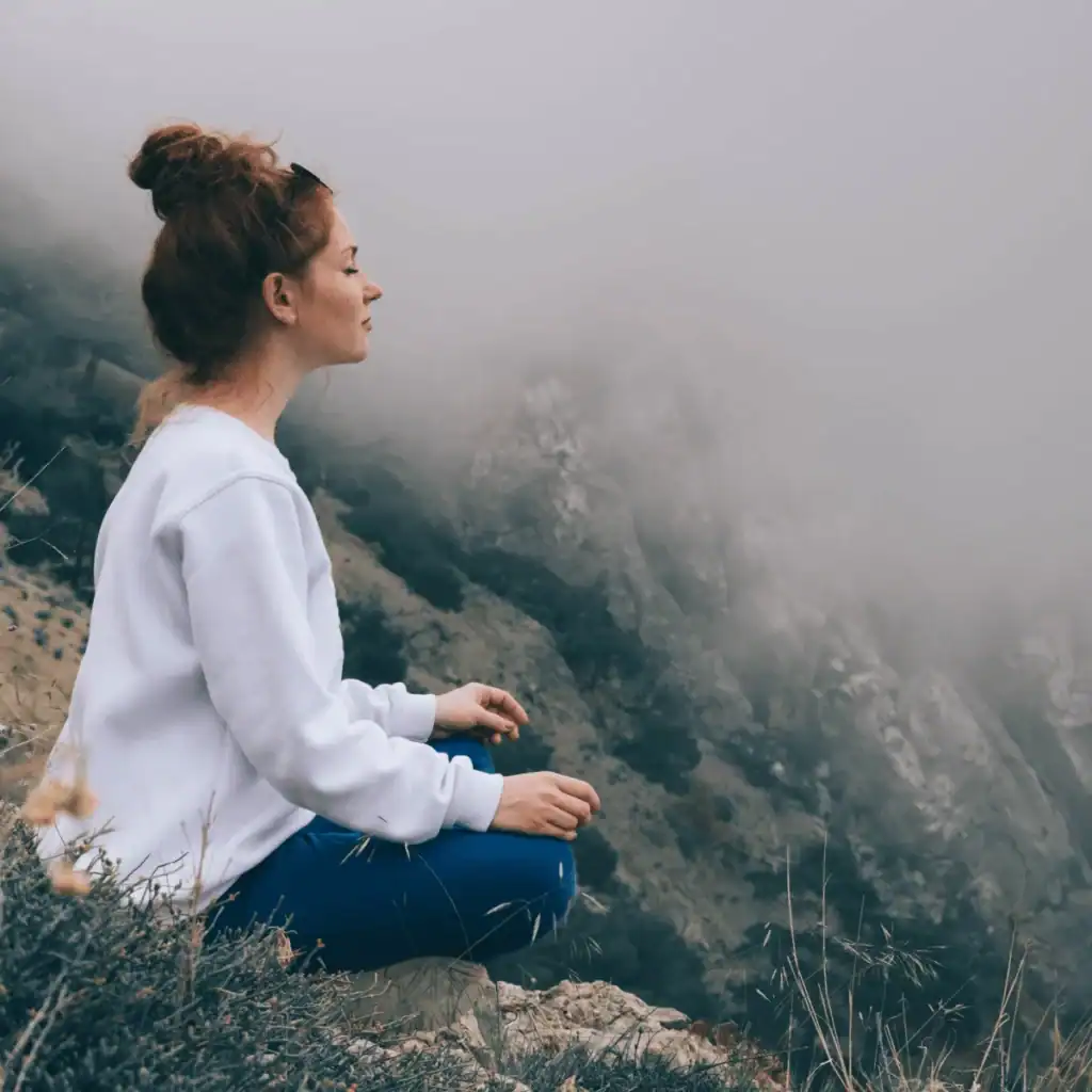 Woman meditating in the mountains. vibrational alignment manifestation method