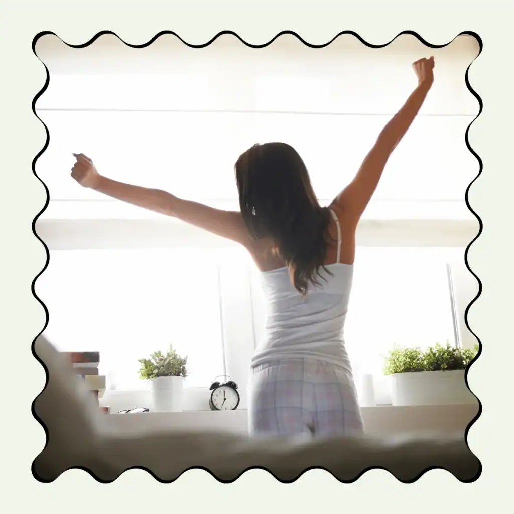 back-view-of-a-woman-stretching-her-arms-out-looking-out-a-window-in-the-morning. Morning Journal Prompts