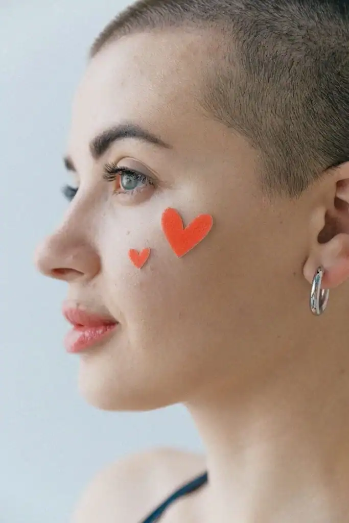 close-up-of-woman-with-a-shaved-head-and-heart-stickers-on-her-face (1)