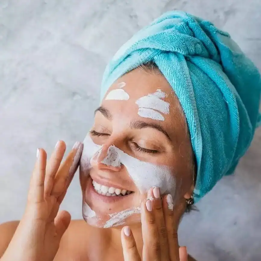 woman-applying-a-face-mask-with-a-blue-towel-wrapped-around-her-head (1)